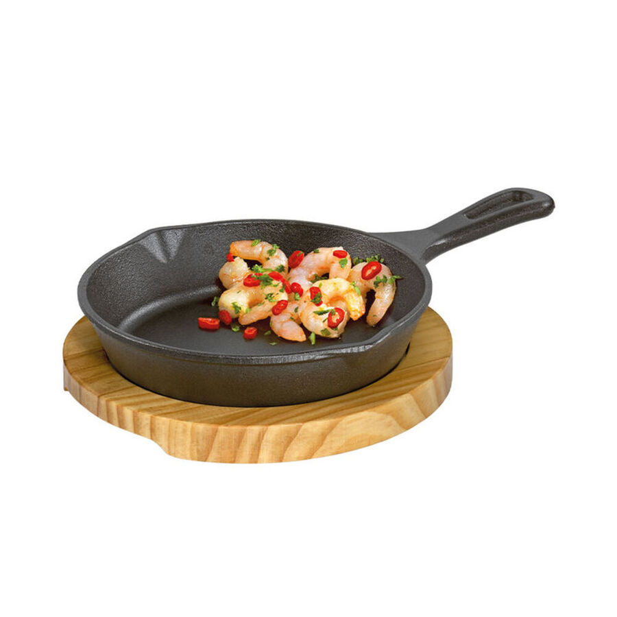 Runde Gusseisen-Grillpfanne auf Pinienholz-Untersetzer