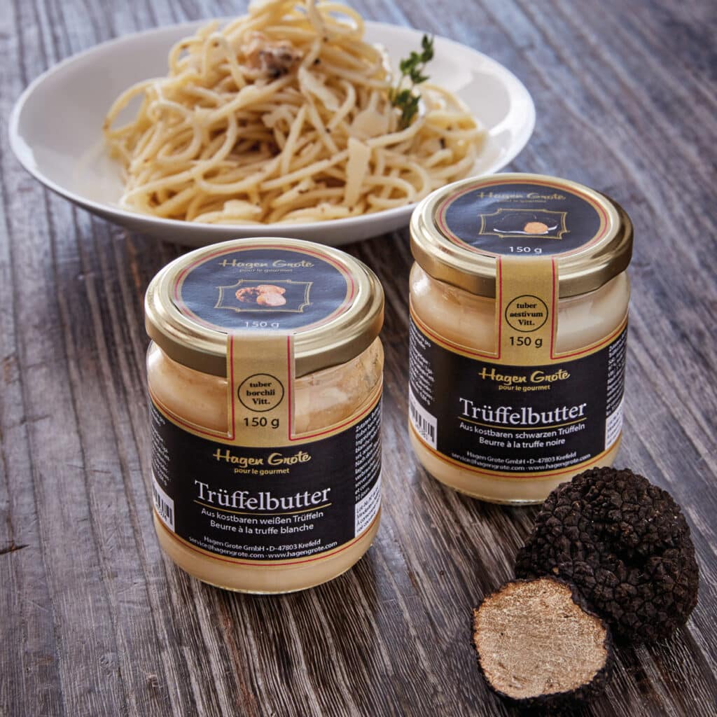 Zwei Gläser Trüffelbutter von Hagen Grote vor einem Teller Pasta und frischer schwarzer Trüffel.