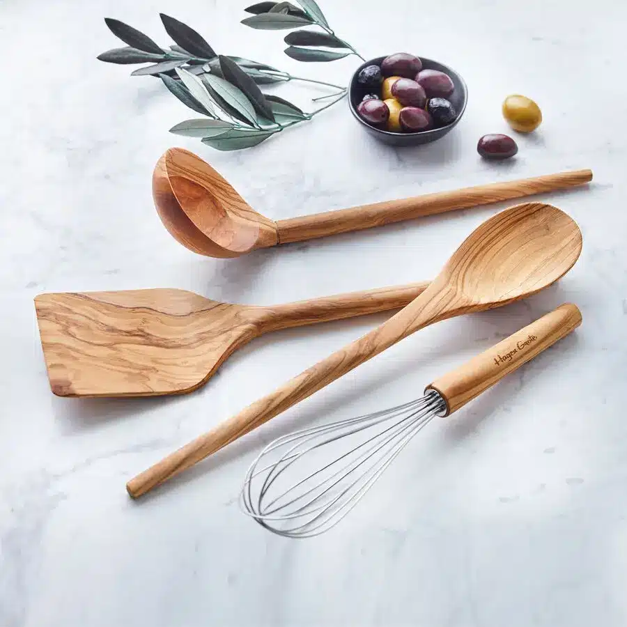 Küchenhelfer-Set aus Olivenholz mit Kochlöffeln, Pfannenwender und Schneebesen auf Marmoroberfläche