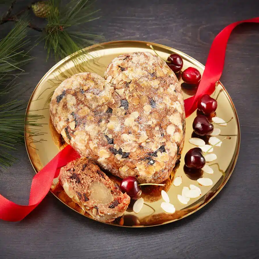 Herzförmiger Weihnachtsstollen mit Puderzucker – gefüllt mit Trockenfrüchten und Mandeln auf festlichem Teller