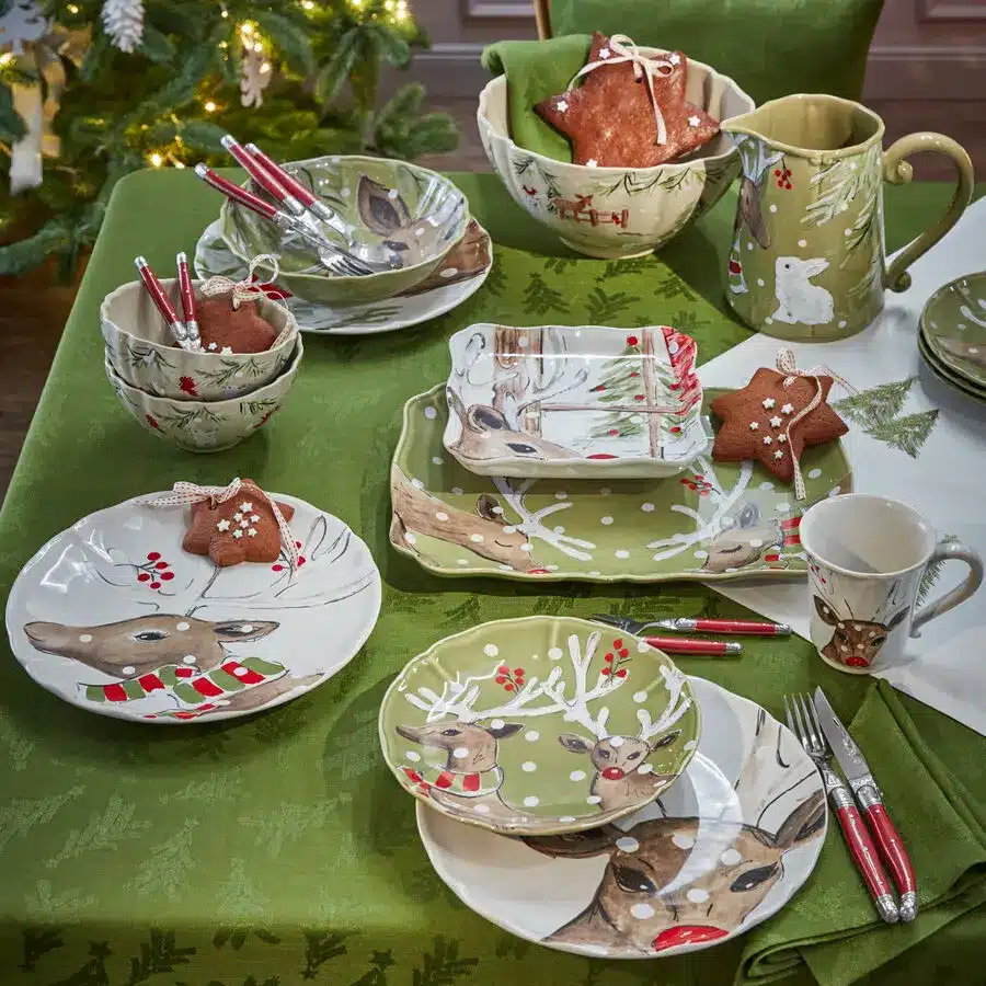 Weihnachtliches Geschirr mit Rentiermotiven auf grün gedecktem Tisch