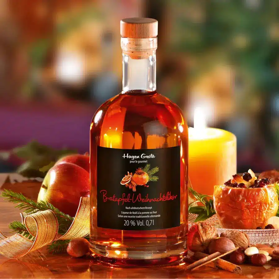 Bratapfel-Weihnachtslikör mit Glas, Kerze und winterlicher Dekoration