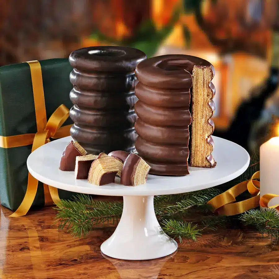 Königlicher Baumkuchen in Vollmilch- und Zartbitterschokolade, geschnitten auf weißer Tortenplatte