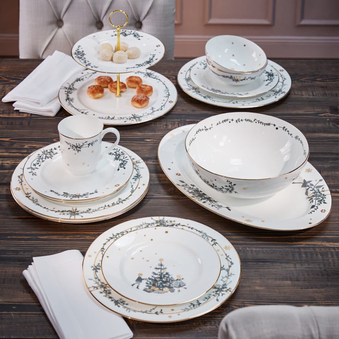 Weißes Weihnachtsgeschirr mit Goldrand und Tannenmotiv, festlich gedeckt