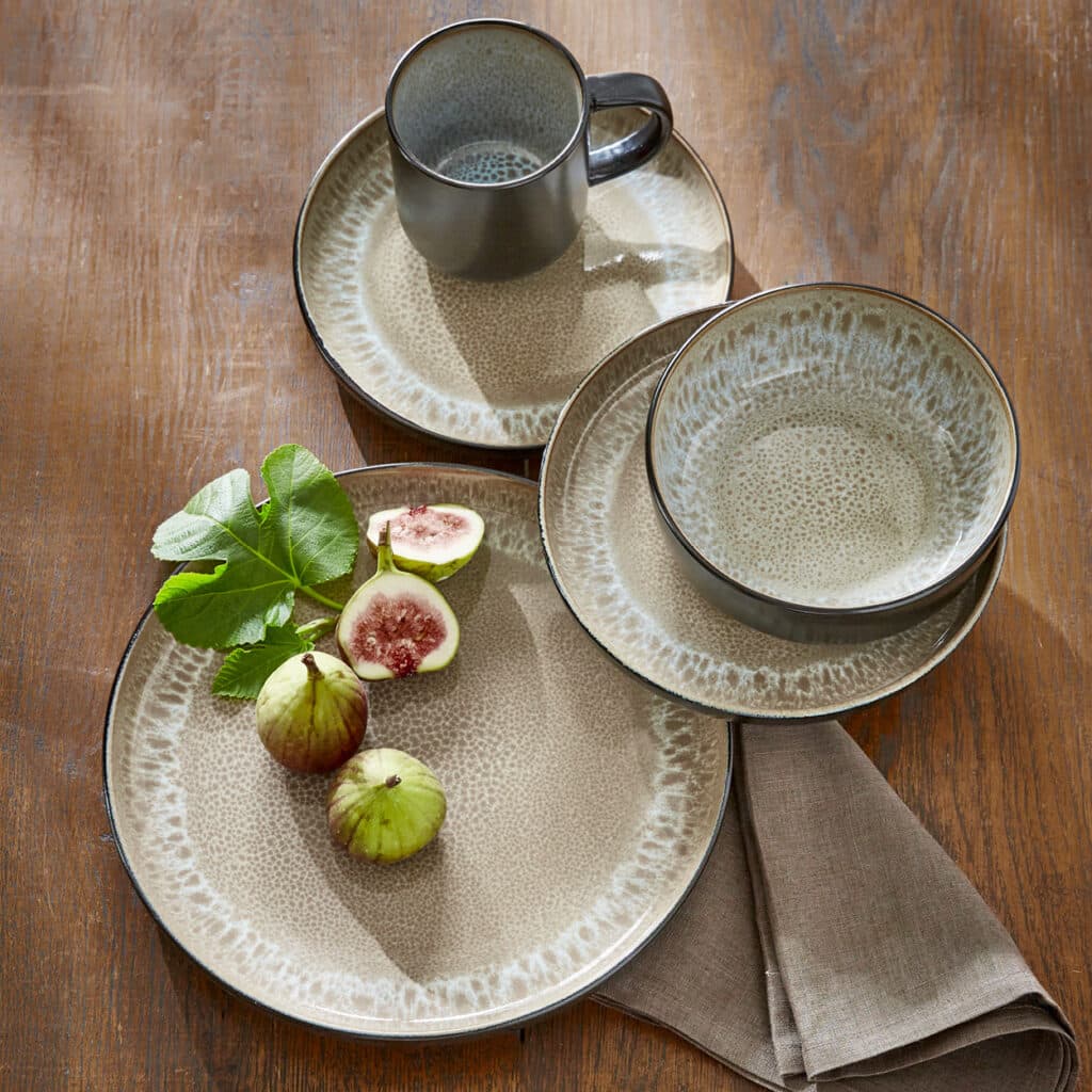 Modernes Steingut-Geschirrset in Beige-Grau mit Feigen auf Holztisch arrangiert