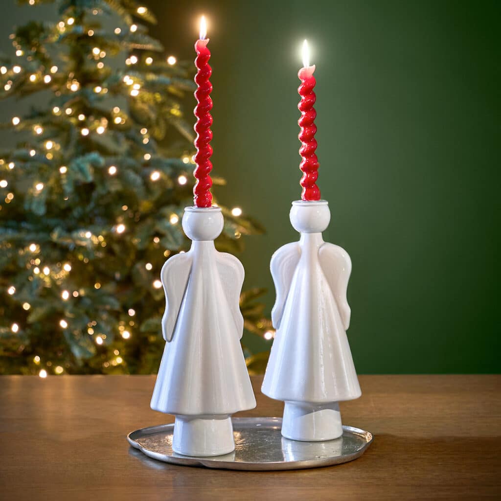 Zwei weiße Engel-Kerzenhalter mit roten Spiral-Kerzen vor Weihnachtsbaum