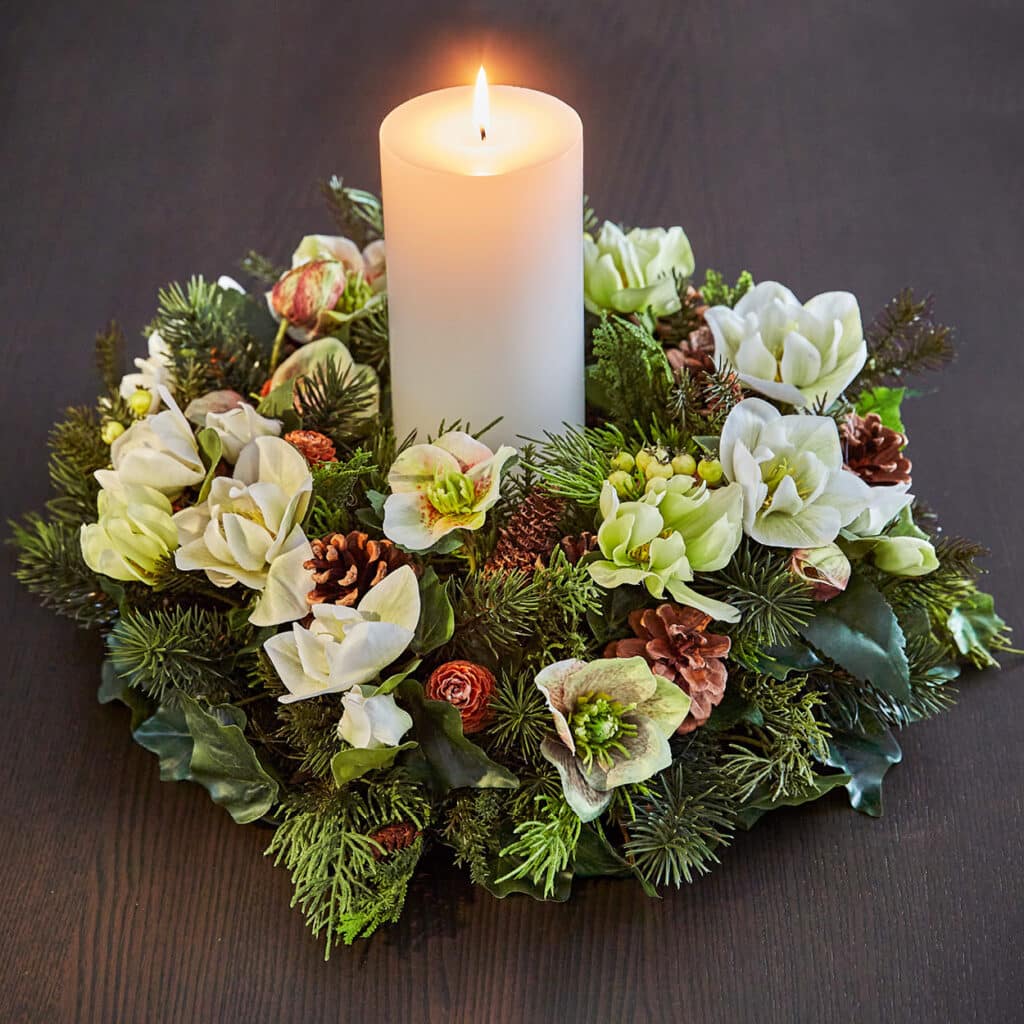 Adventskranz mit weißen Blüten, Tannenzweigen, Zapfen und großer Stumpenkerze