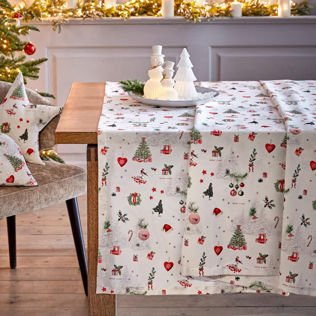 Weihnachtstisch mit weißer Tischdecke im Festtagsmotiv, dekoriert mit Schneemann-Figuren
