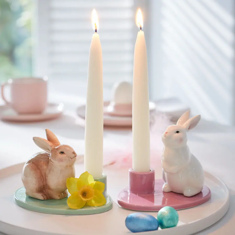 Pastellige Kerzenhalter mit Hasenfiguren und Stabkerzen als Oster-Tischdeko